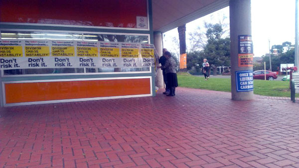 Sophie and Greg Mirabella removing posters wrapped around the Wangaratta Tafe polling booth