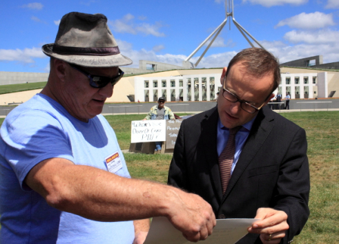 Loz Lowrey shows Adam Bandt the Peoples Vote of No Confidence in the Abbott Government.(Photo: Wayne Jannson).